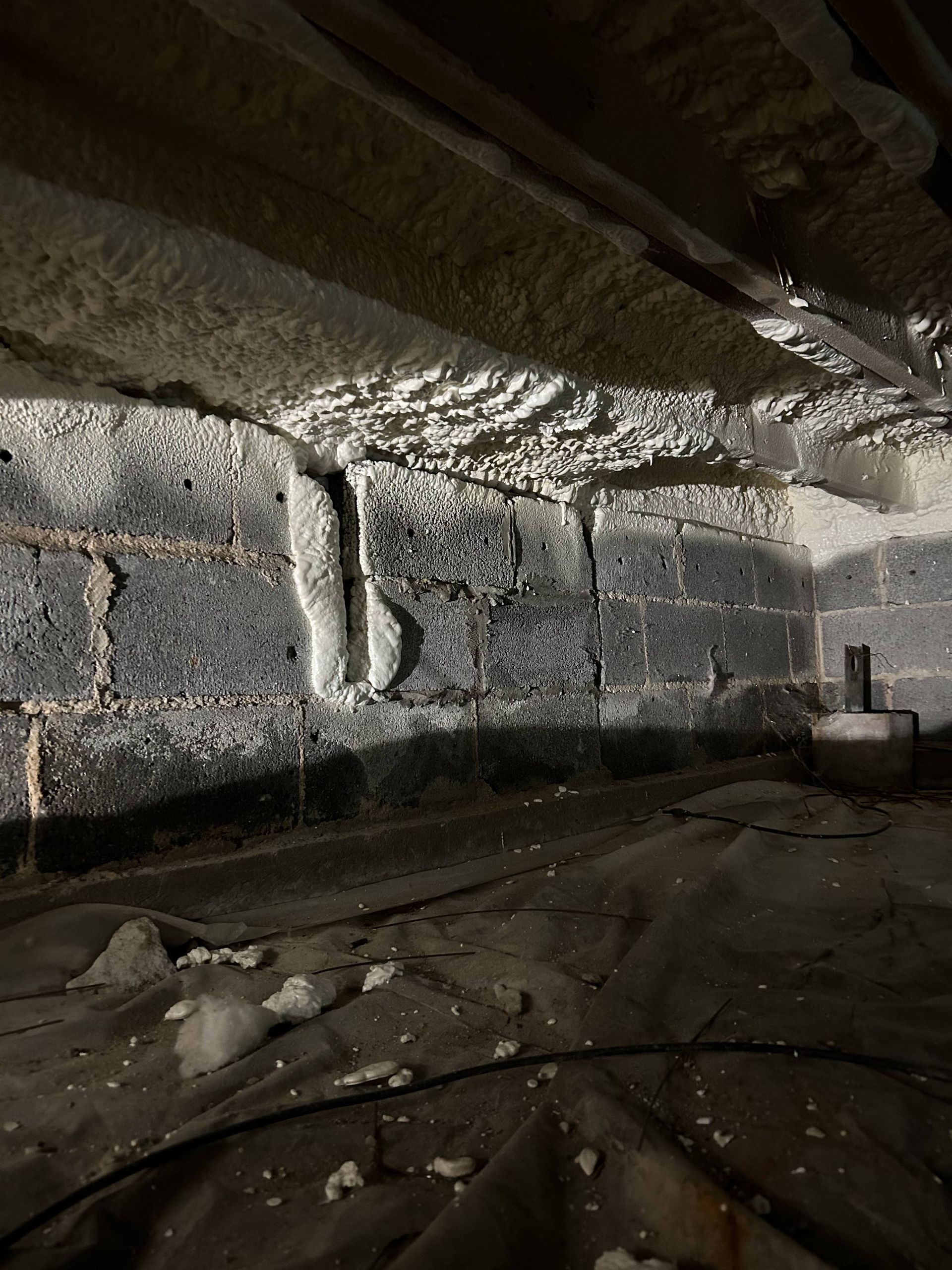Rocky cave interior with rough stone walls, a low ceiling, and a small bucket on the floor