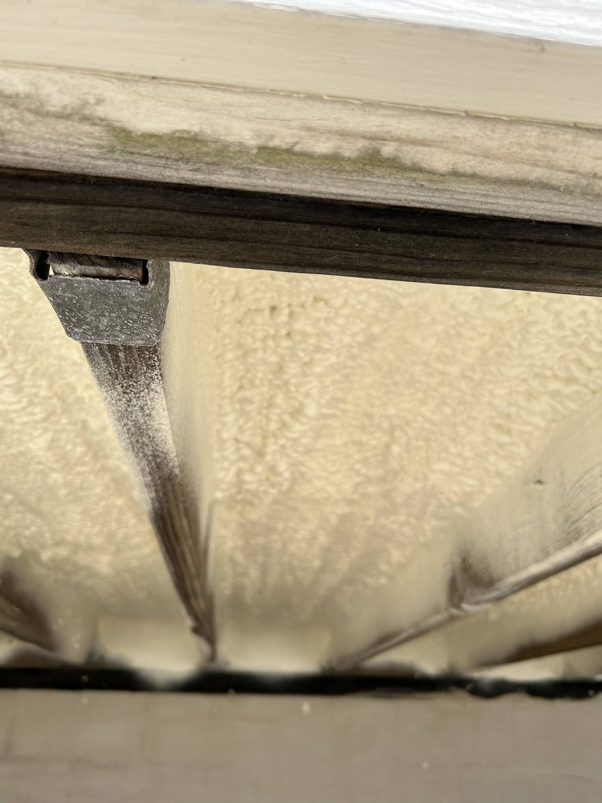 Close-up of beige insulation with a black strip and a small metal bracket near the top edge