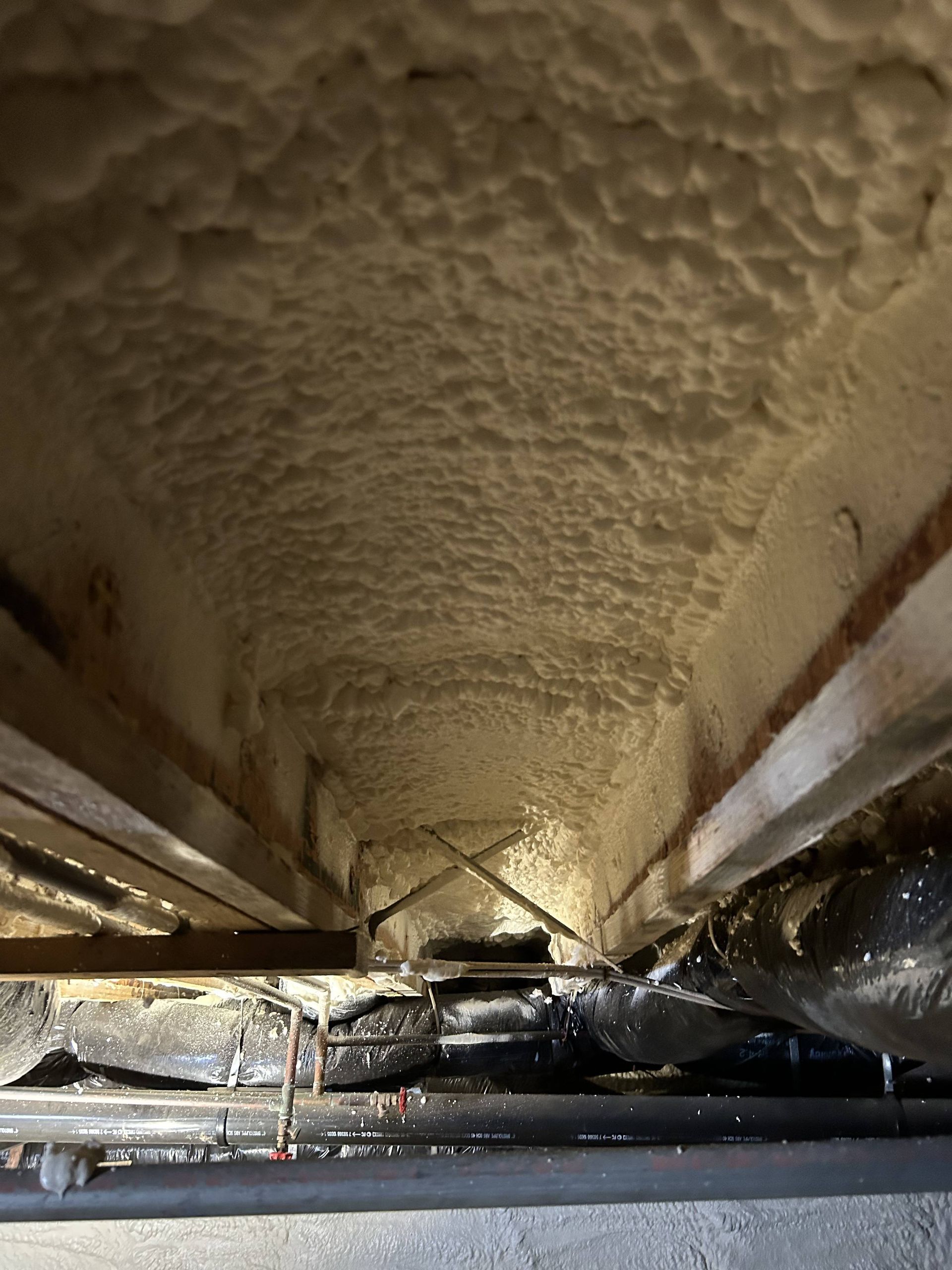Foamy insulation and reflective metal lining inside a narrow industrial duct or tunnel