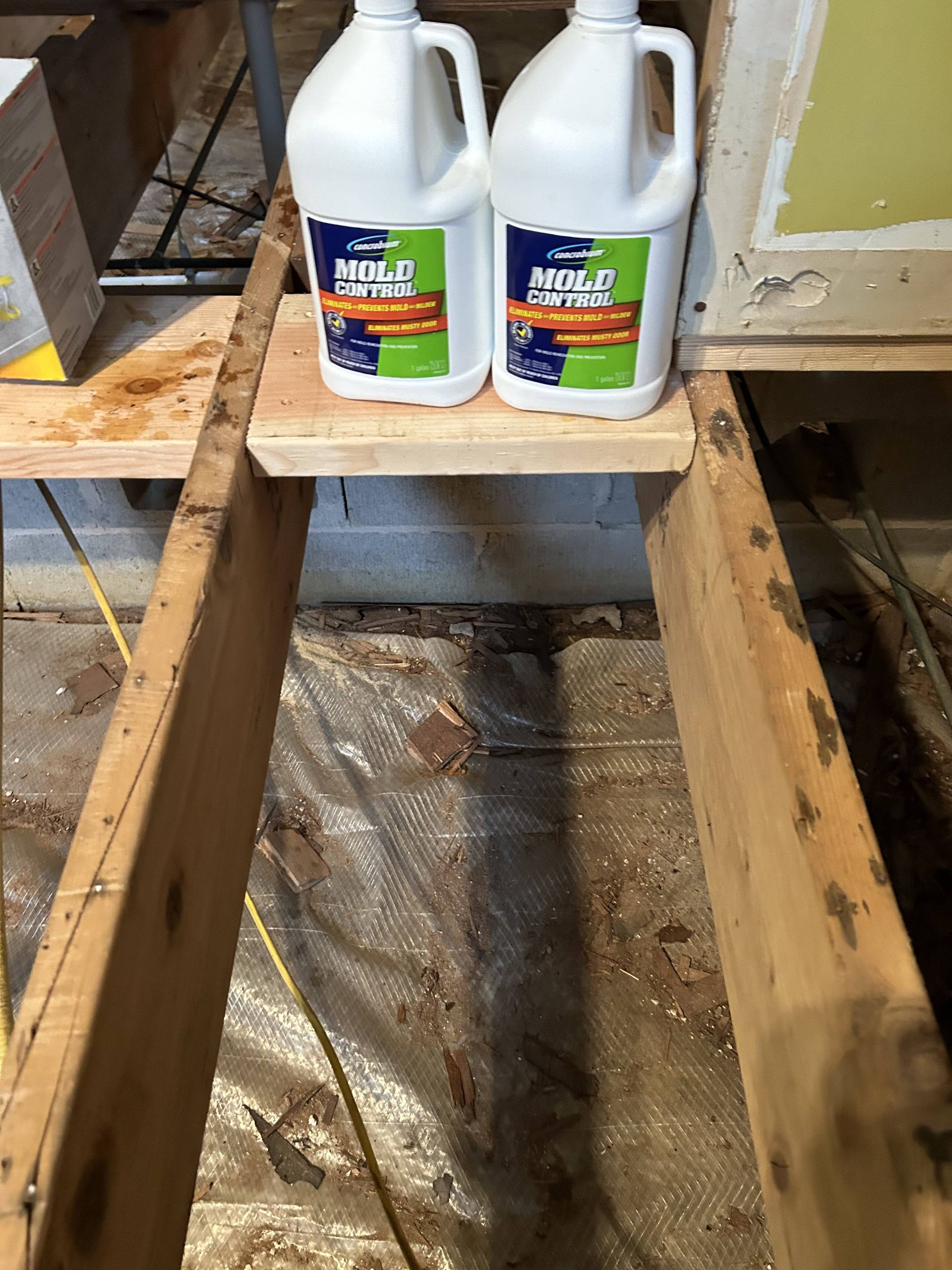 Two white gallon jugs of cleaning solution on a wooden pallet in a warehouse aisle