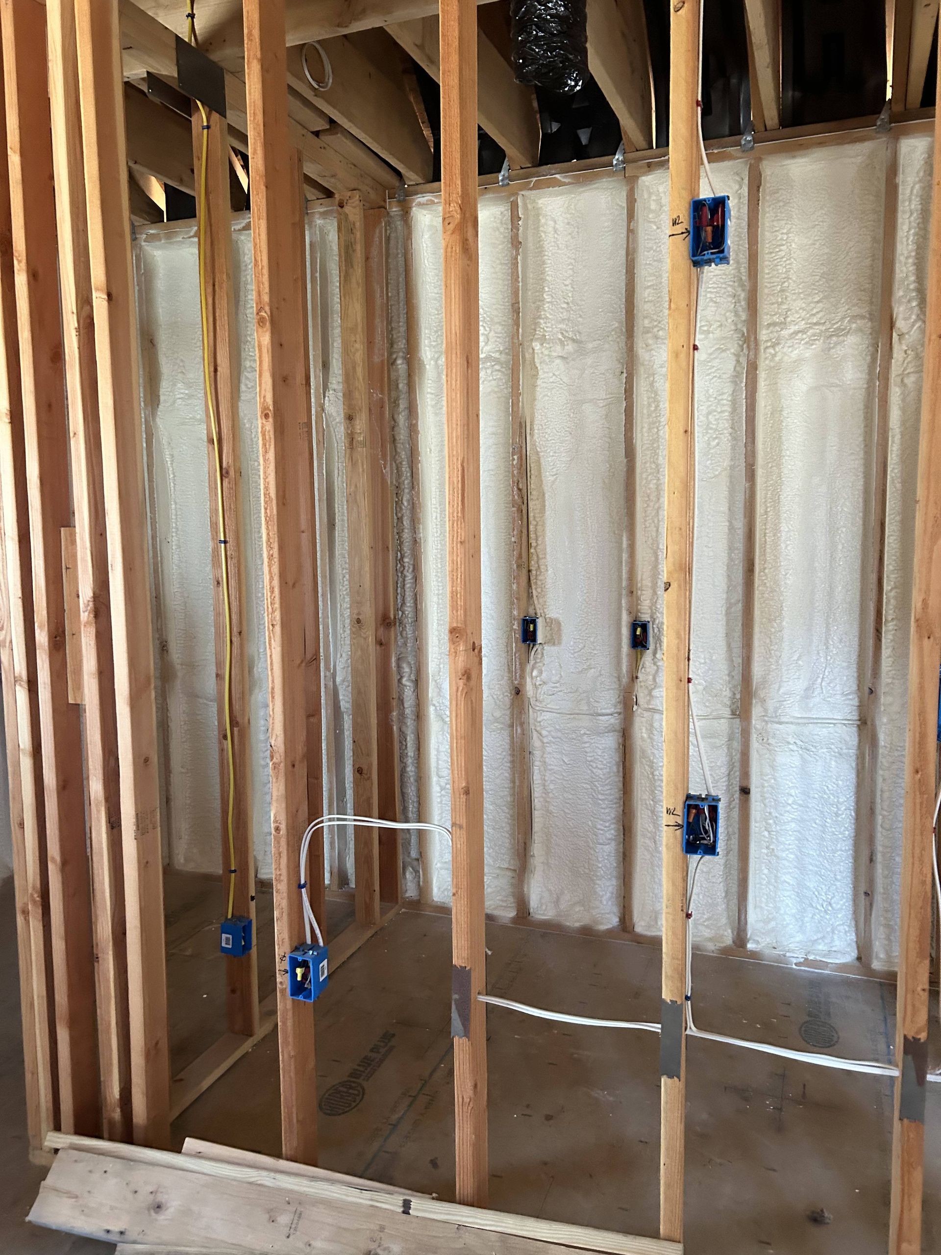 Exposed wall framing with insulation and electrical boxes in an unfinished interior room