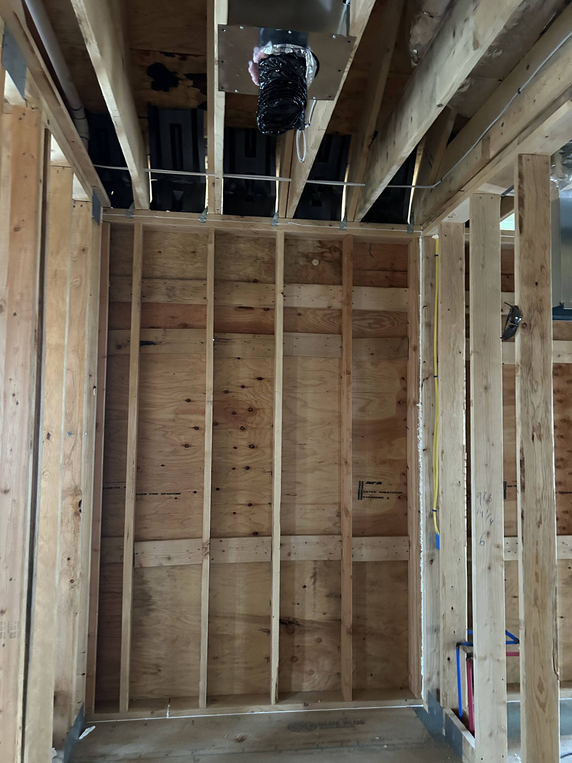 Unfinished framed room with exposed studs, plywood walls, and ceiling joists.