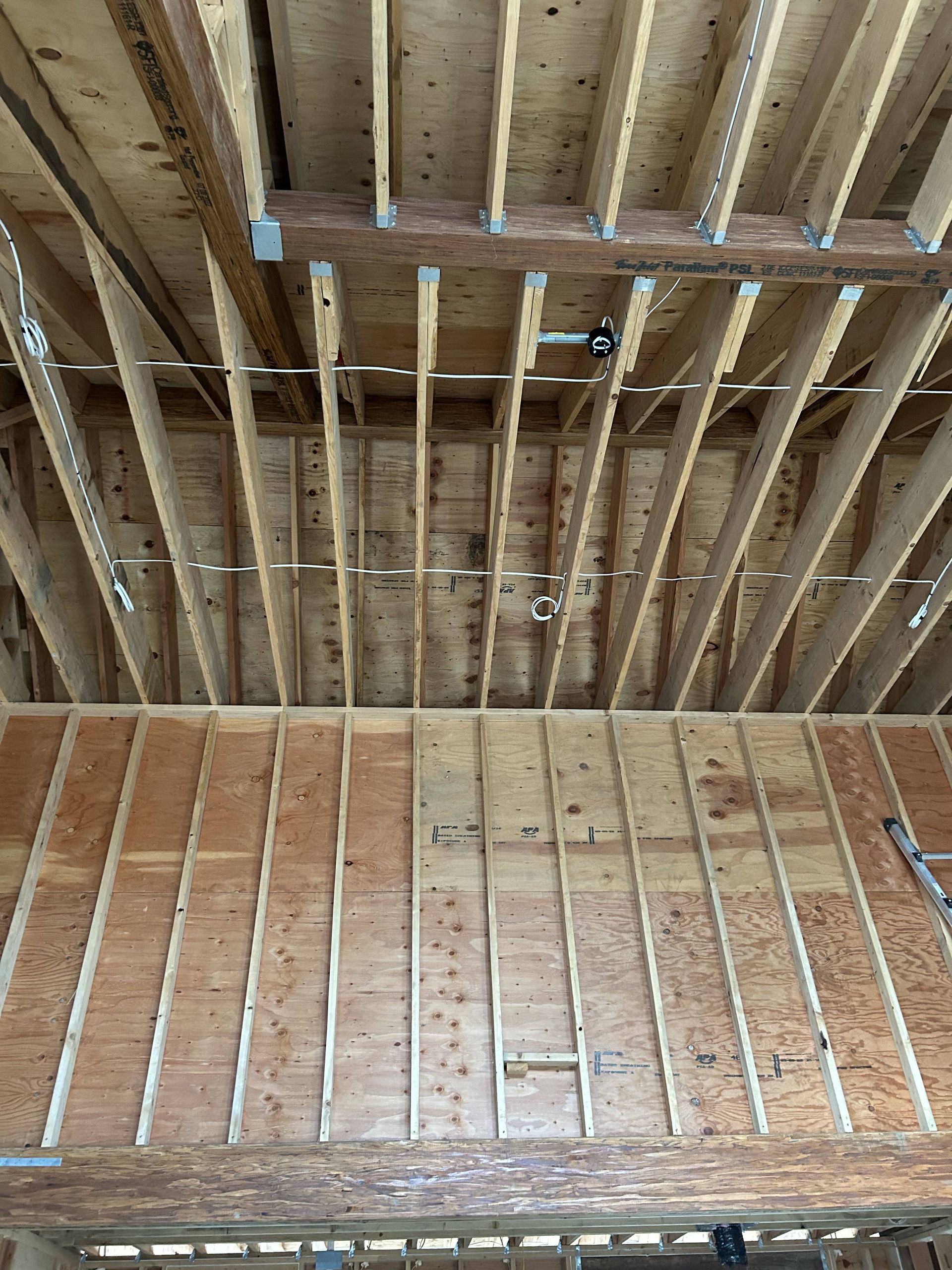 Exposed wooden ceiling joists and framed wall studs in an unfinished interior under construction