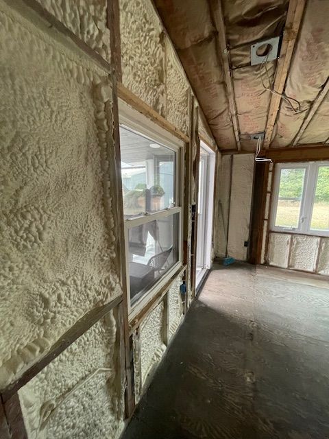 Narrow unfinished interior hallway with exposed walls, windows, and a concrete floor