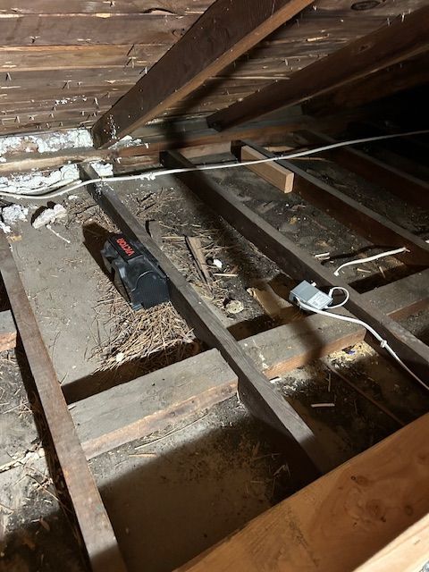 Attic floor with exposed beams, insulation, and tools on wooden joists