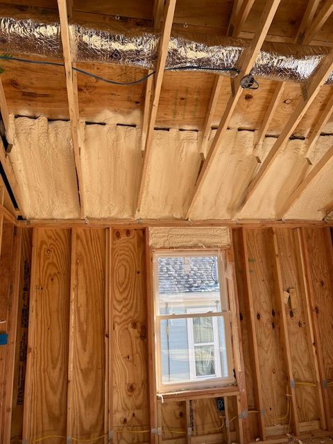 Unfinished wooden room with exposed ceiling insulation and a small window letting in daylight.