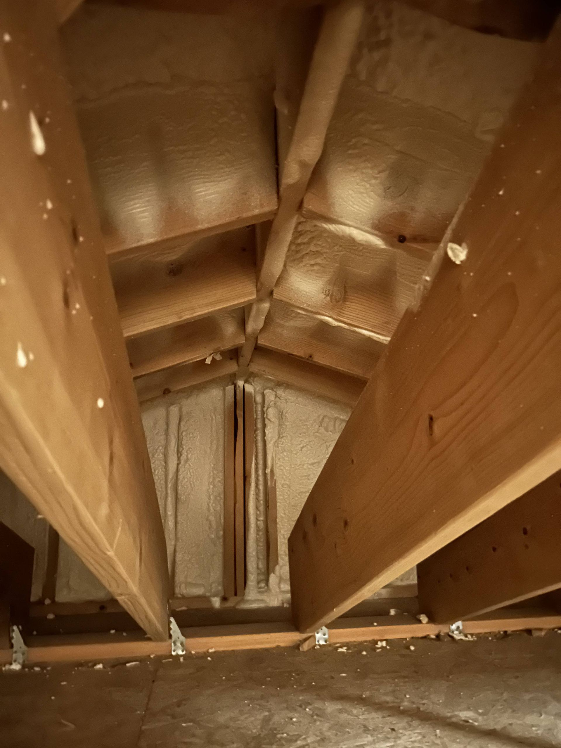 Interior view of an unfinished wooden attic or shaft with beams and insulation panels