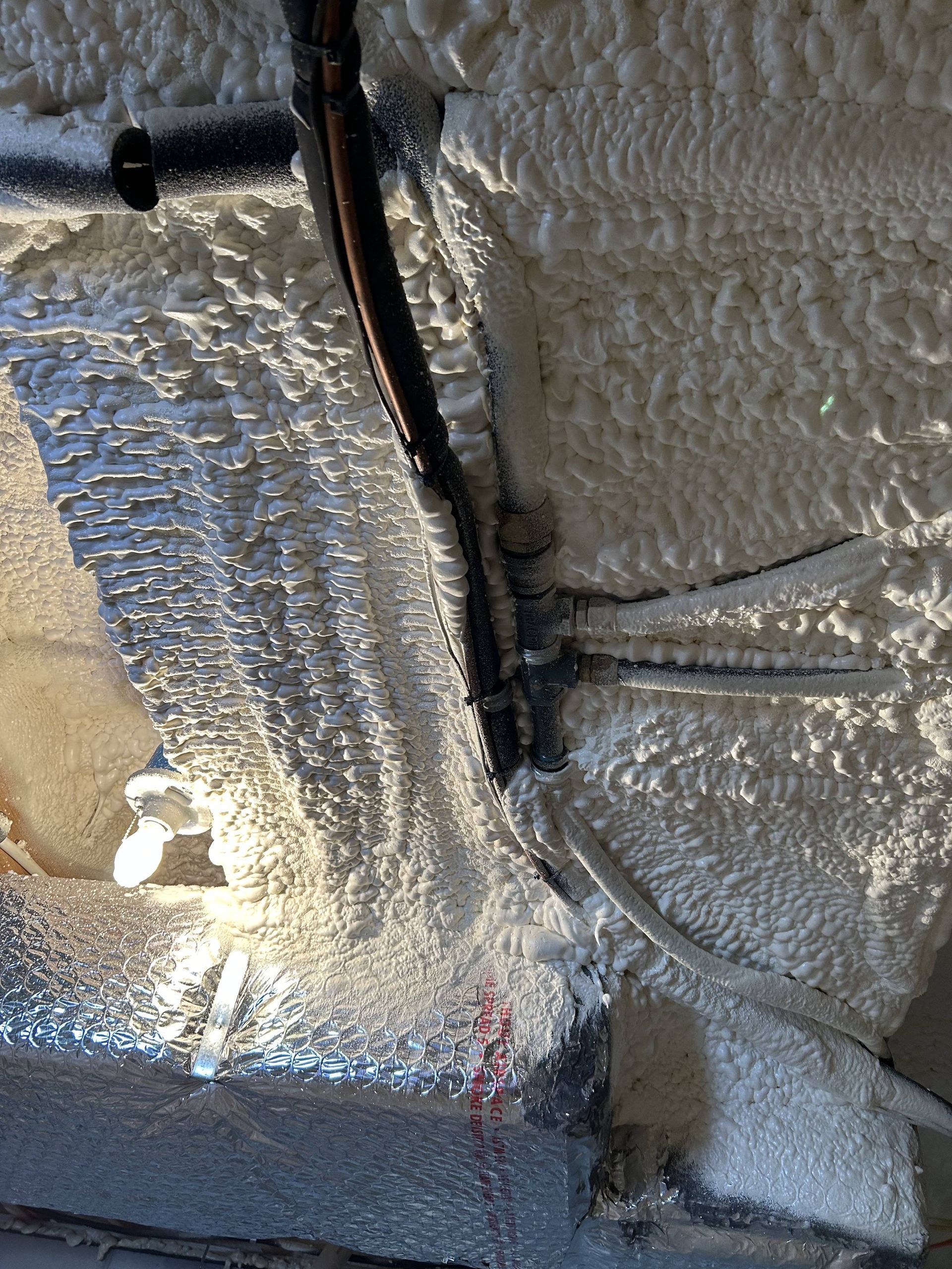 Foam-insulated wall with black cable and a small pipe protruding near the top left