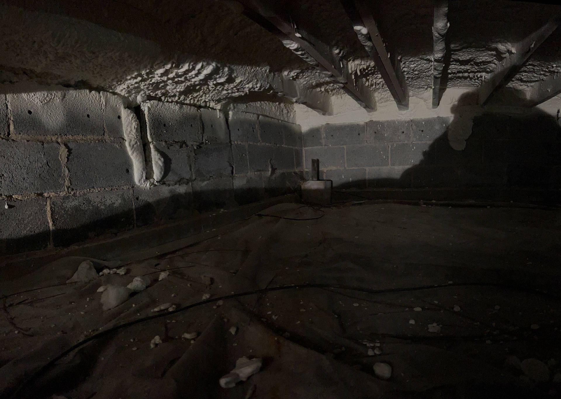 Dark abandoned concrete room with debris on the floor and exposed beams overhead