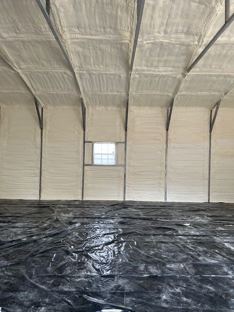 Empty warehouse interior with insulated walls, high ceiling, and black plastic covering the floor