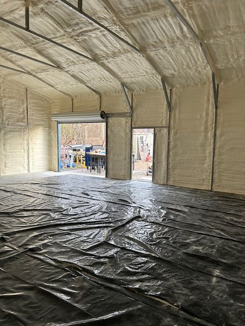 Empty insulated warehouse interior with black floor covering and open doorway to outside