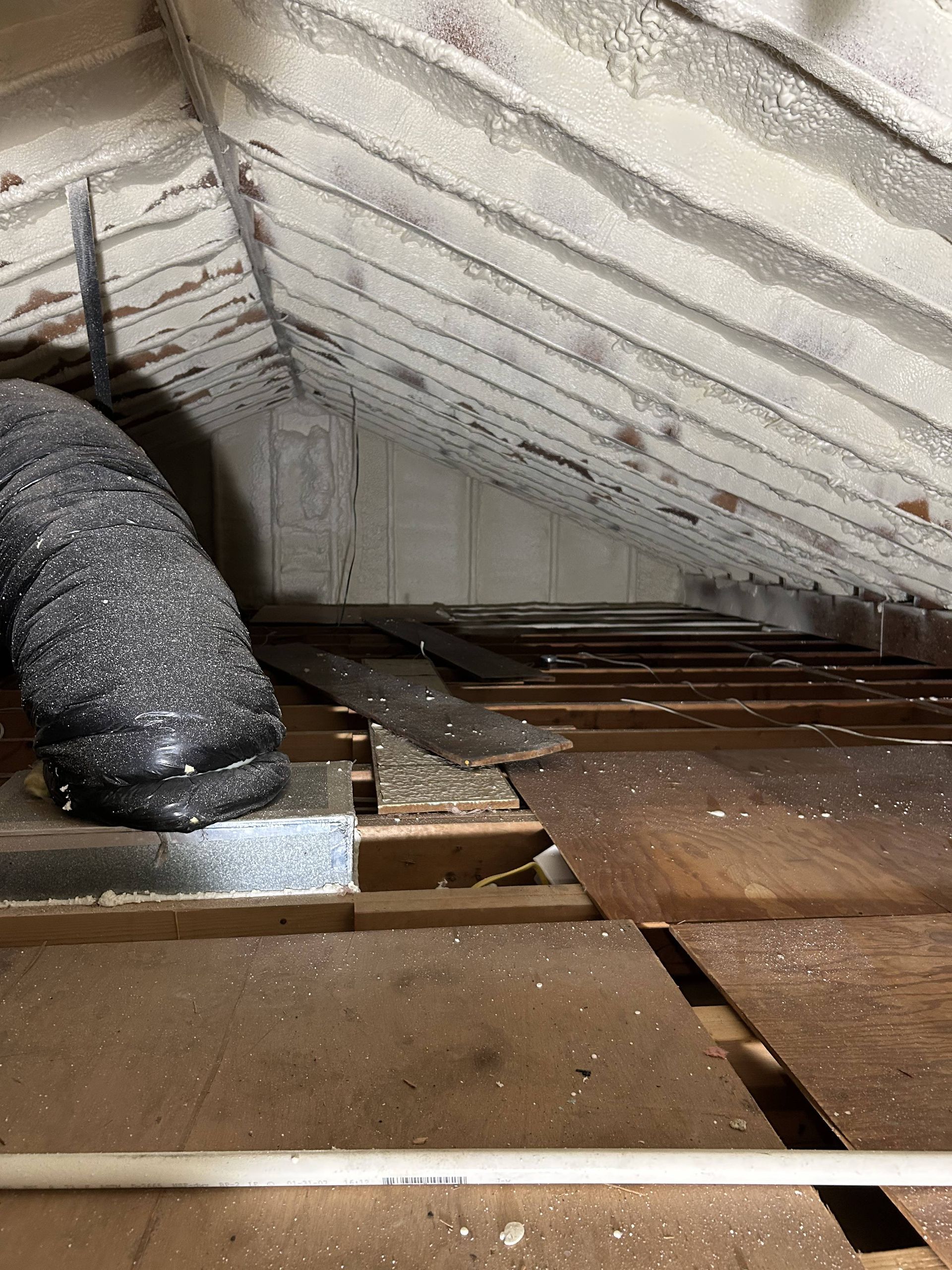 Attic with damaged insulation and exposed beams, showing a rough, unfinished floor area.