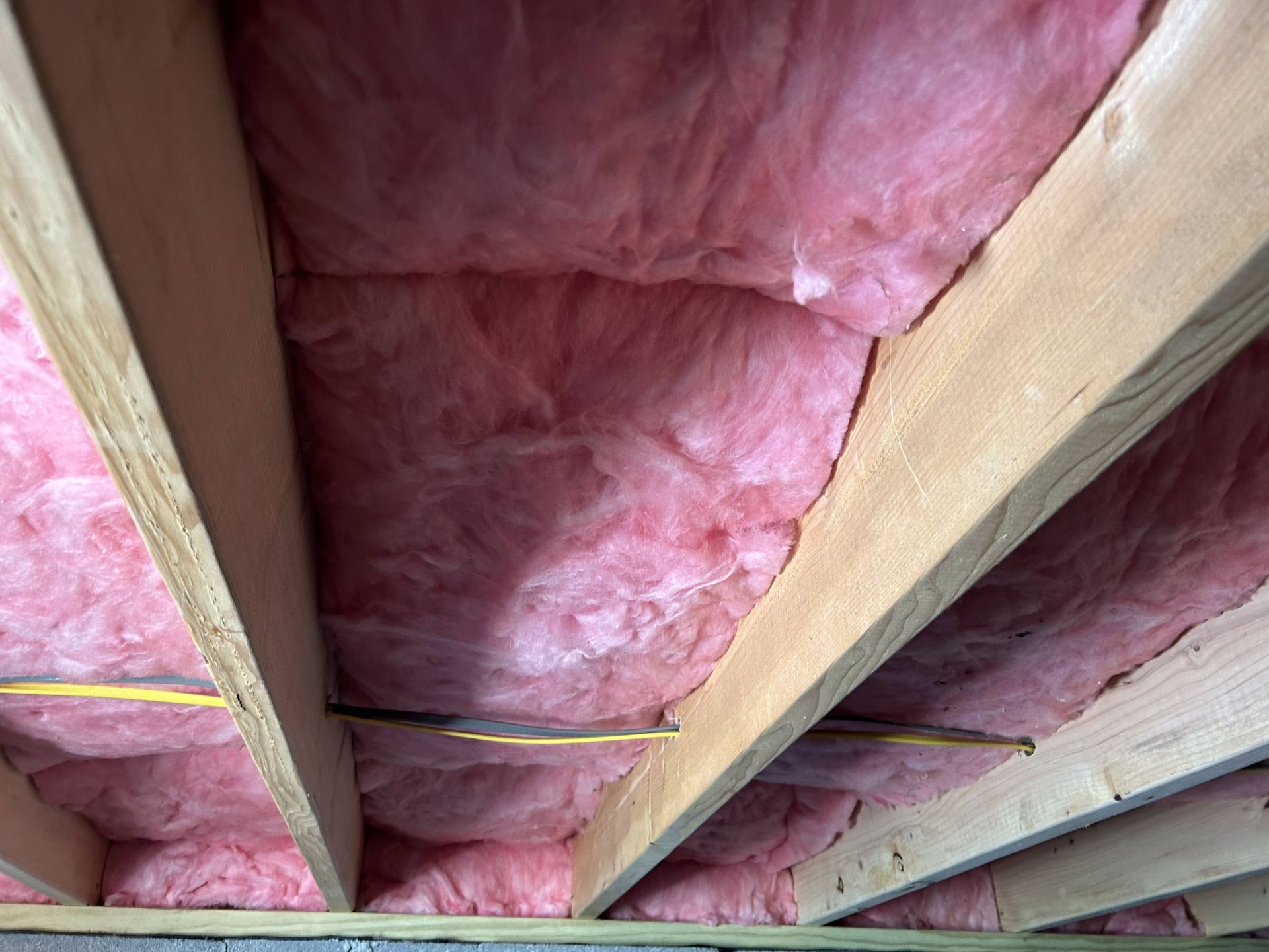 Pink insulation batts between exposed wooden ceiling joists