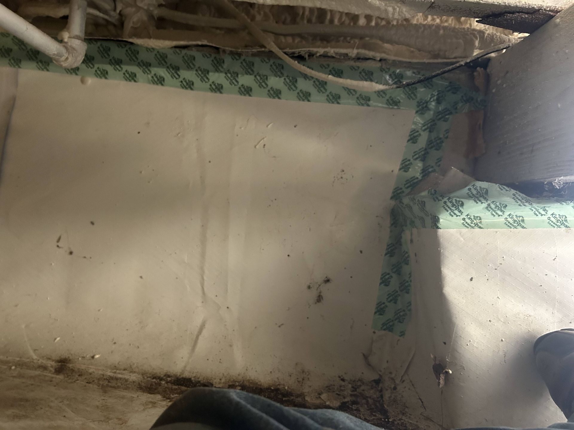 Old, dirty wall and floor corner with peeling paint and green patterned trim in a dim interior