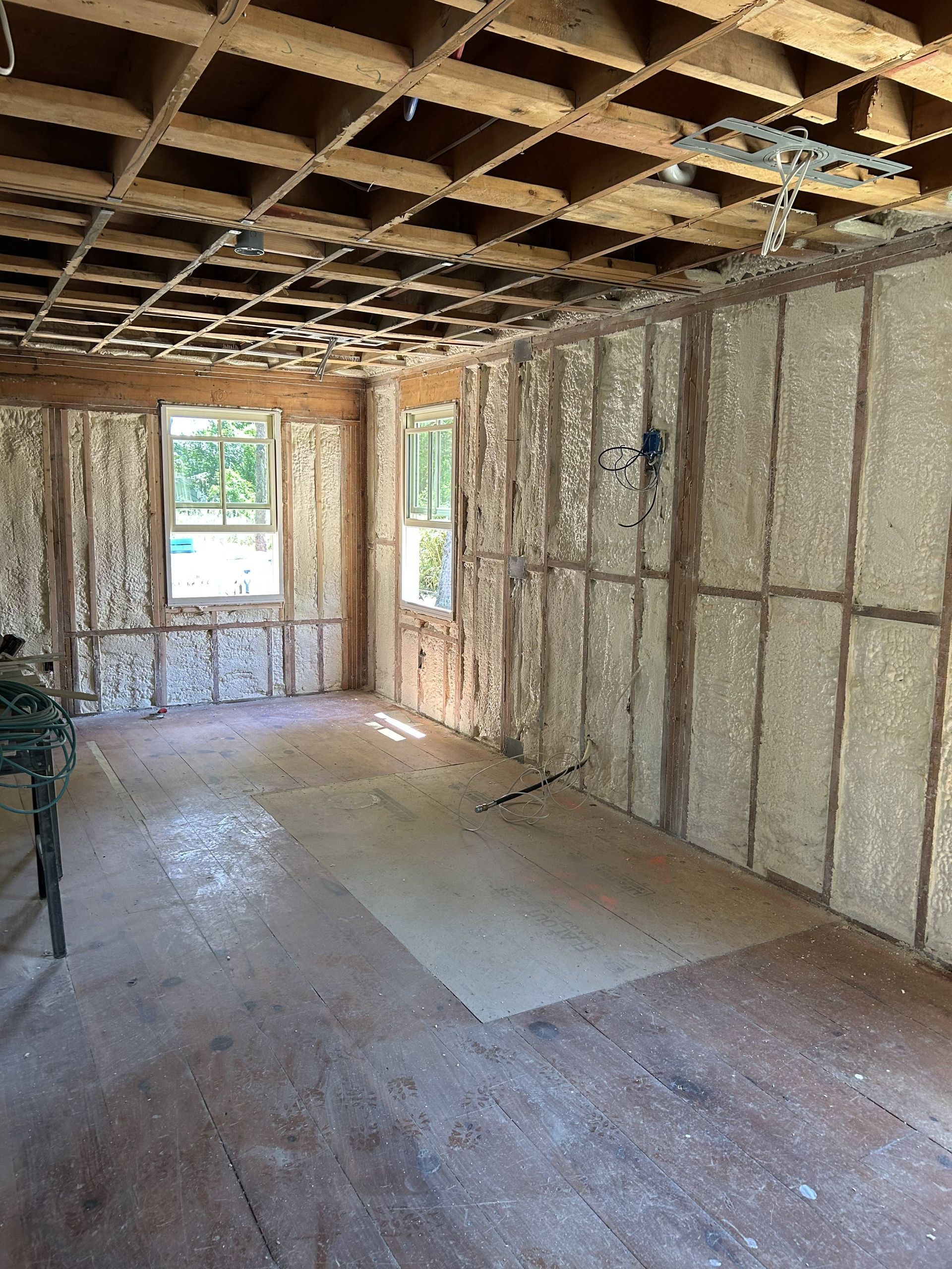 Unfinished room with exposed wall framing, ceiling joists, and a doorway opening to outside light.