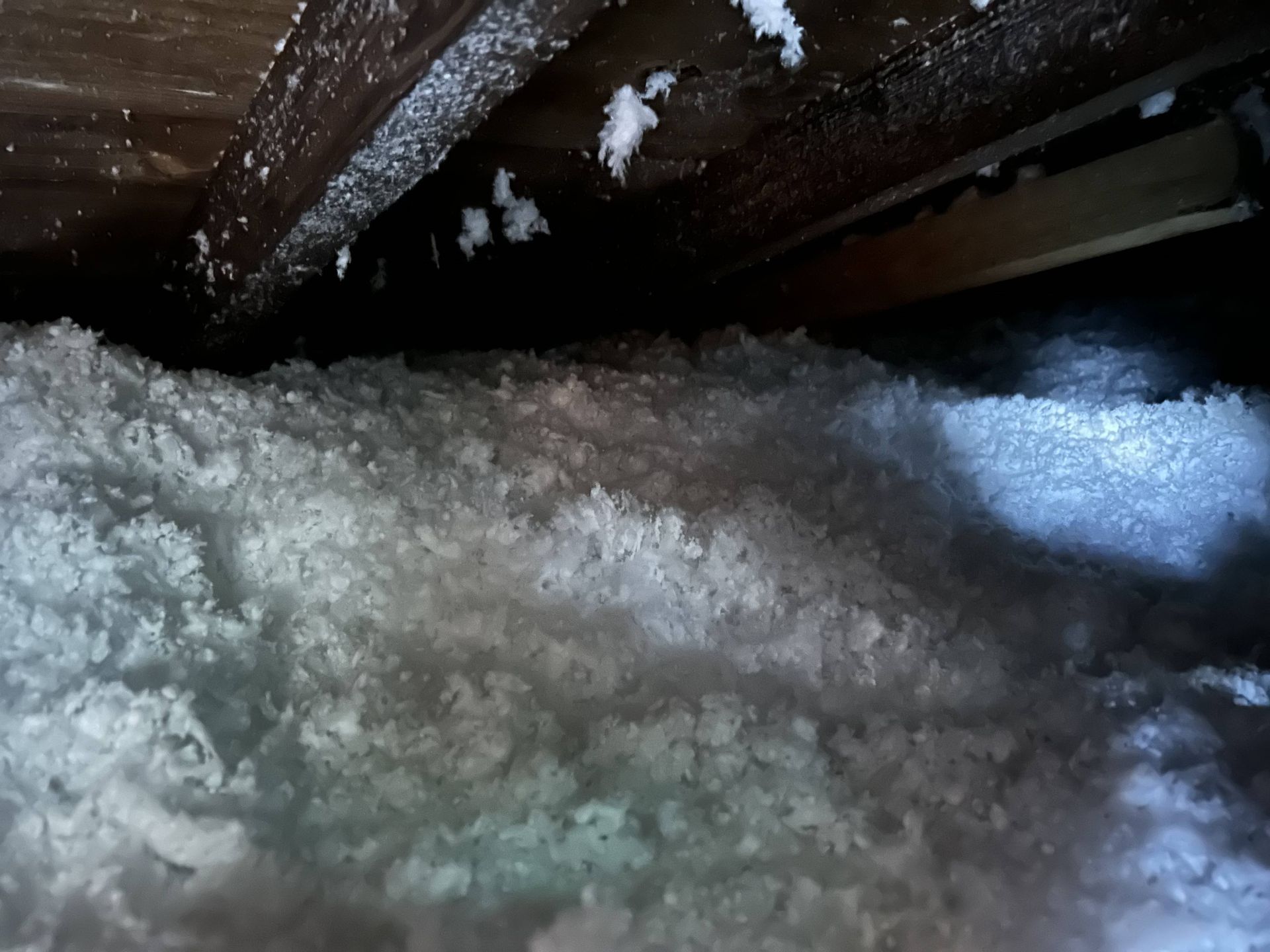 Snow and ice piled under a wooden structure, with light shining on the right side.