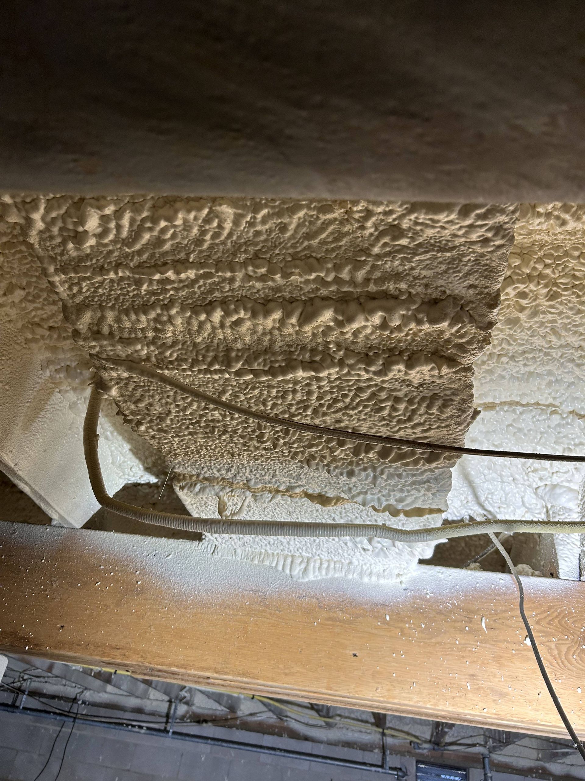 Damaged ceiling with exposed insulation, hanging wires, and cracked plaster above a window