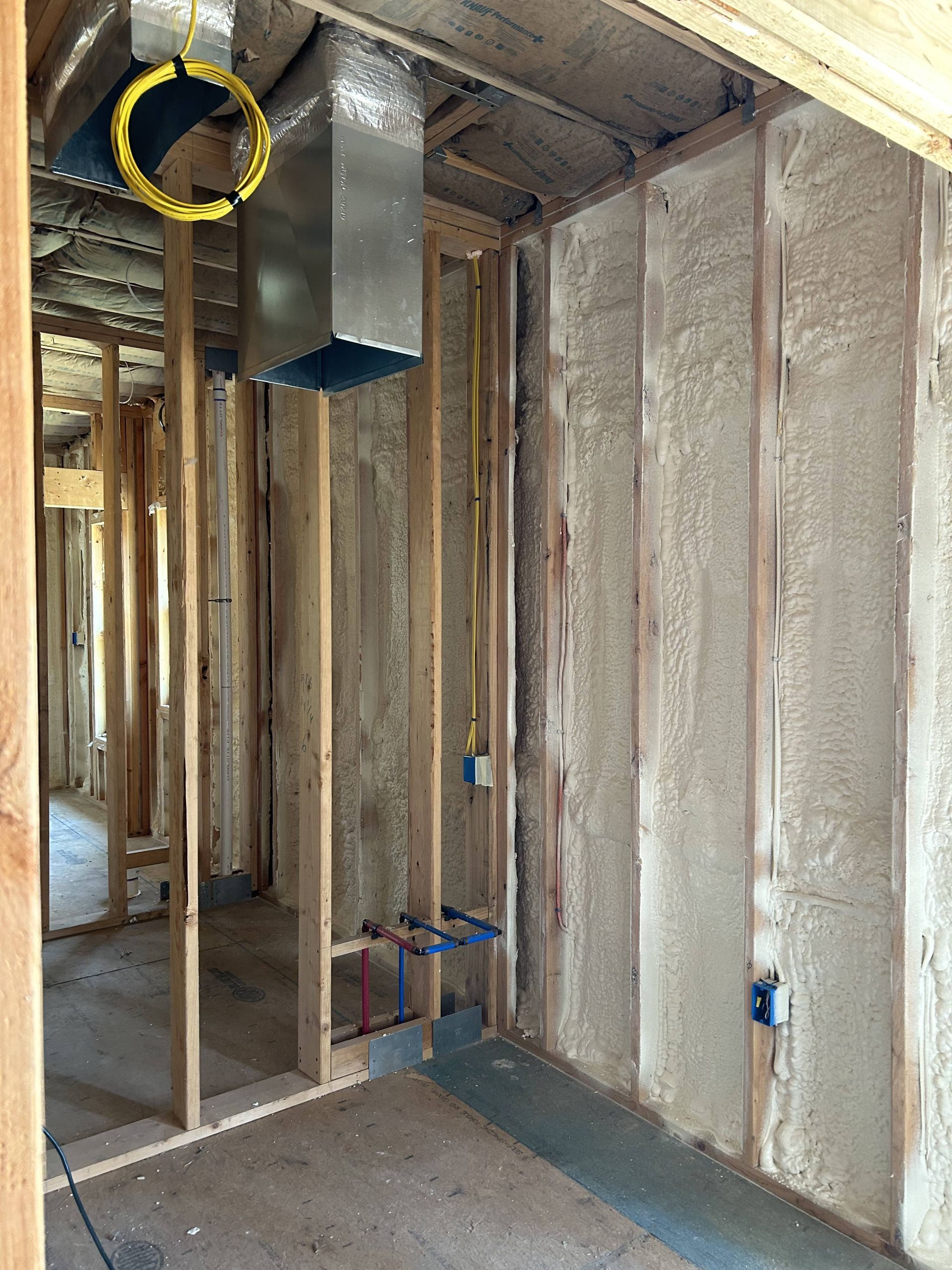 Unfinished room with exposed framing, insulation, ductwork, and marked ceiling area during construction.