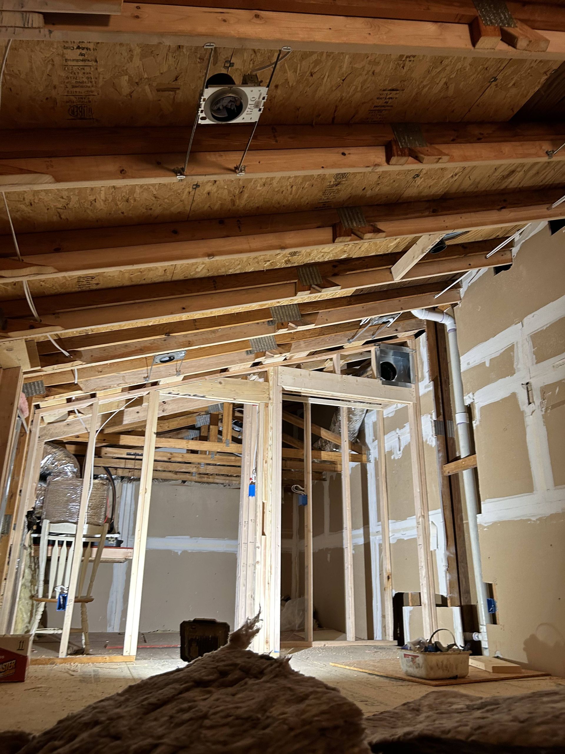 Interior of a house under renovation, with exposed wooden beams and unfinished walls.