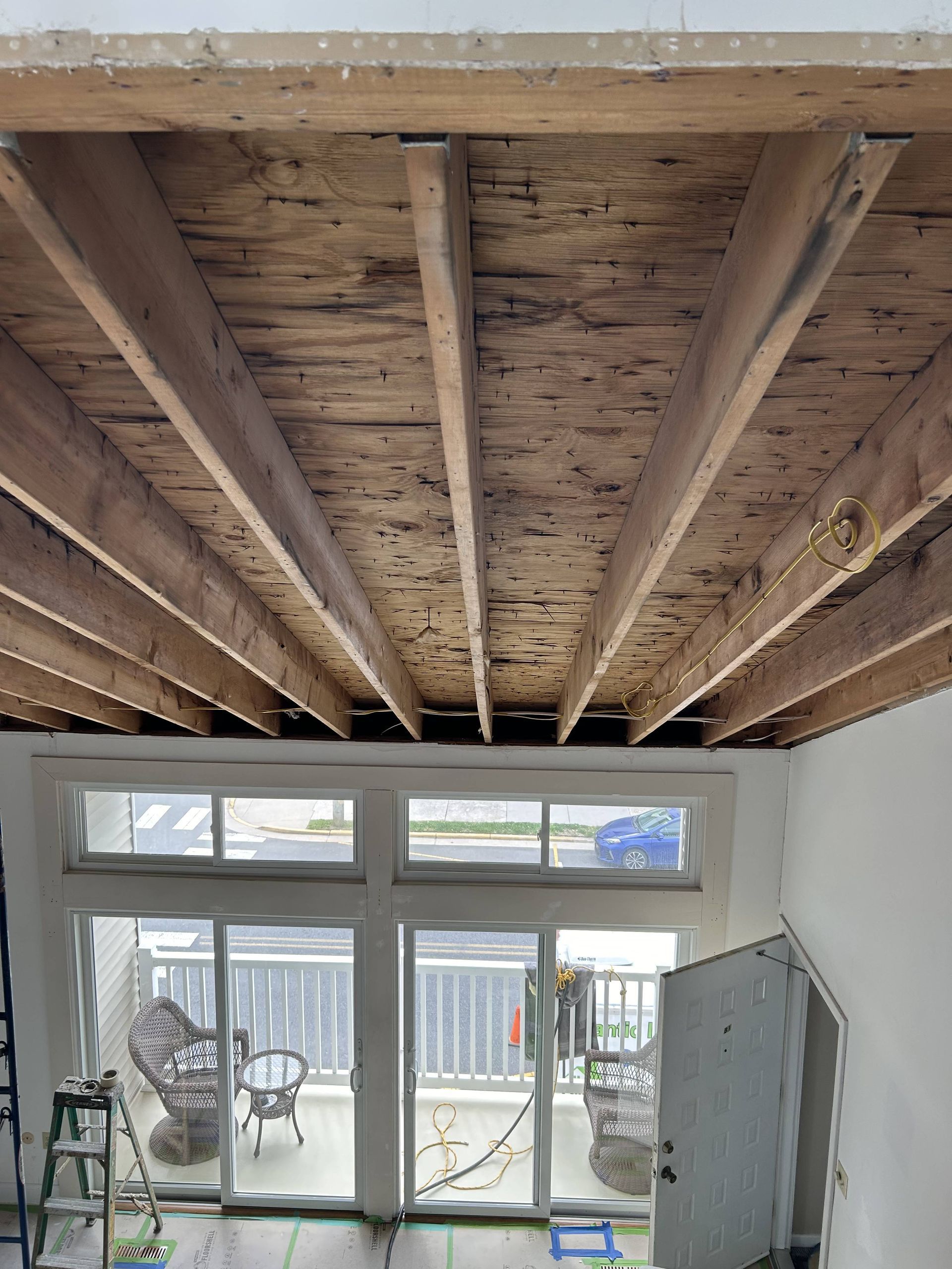Exposed wooden ceiling beams over a bright room with glass doors and windows leading outside