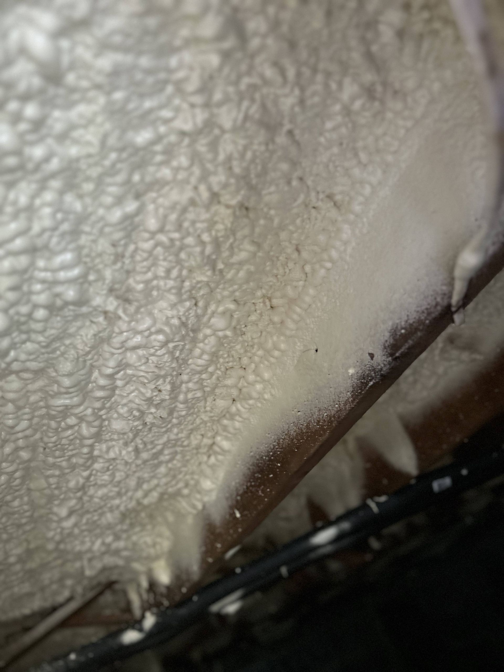 Close-up of a white textured fabric edge with a dark seam and black trim.