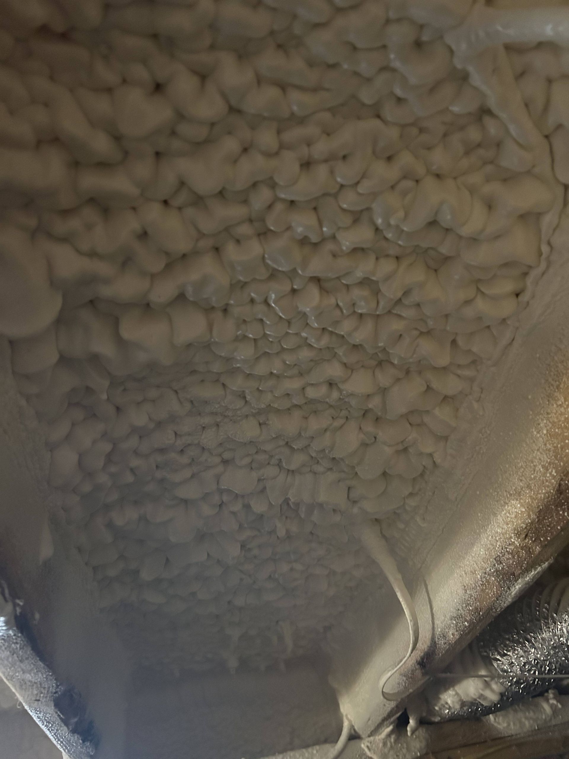 Close-up of beige foam or insulation covering the underside of a surface with a dark edge