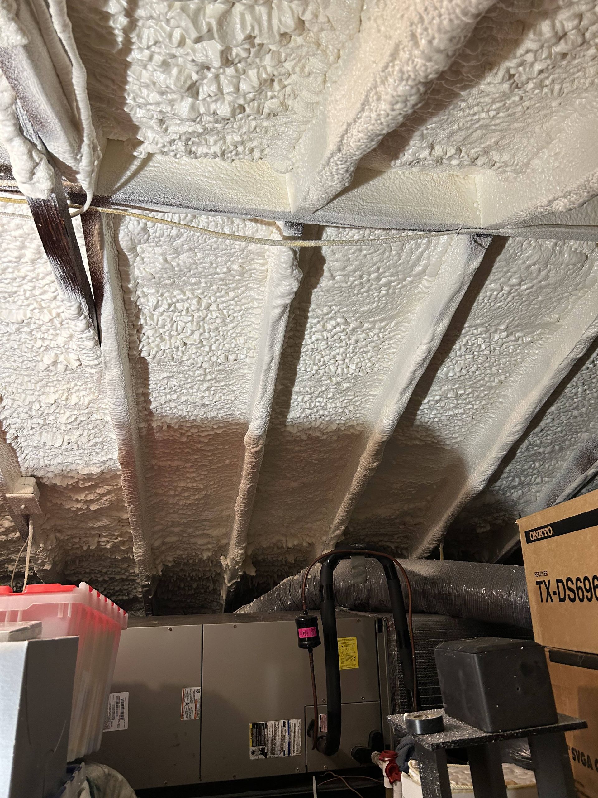 Spray foam-insulated basement ceiling with HVAC equipment and ductwork in a utility room