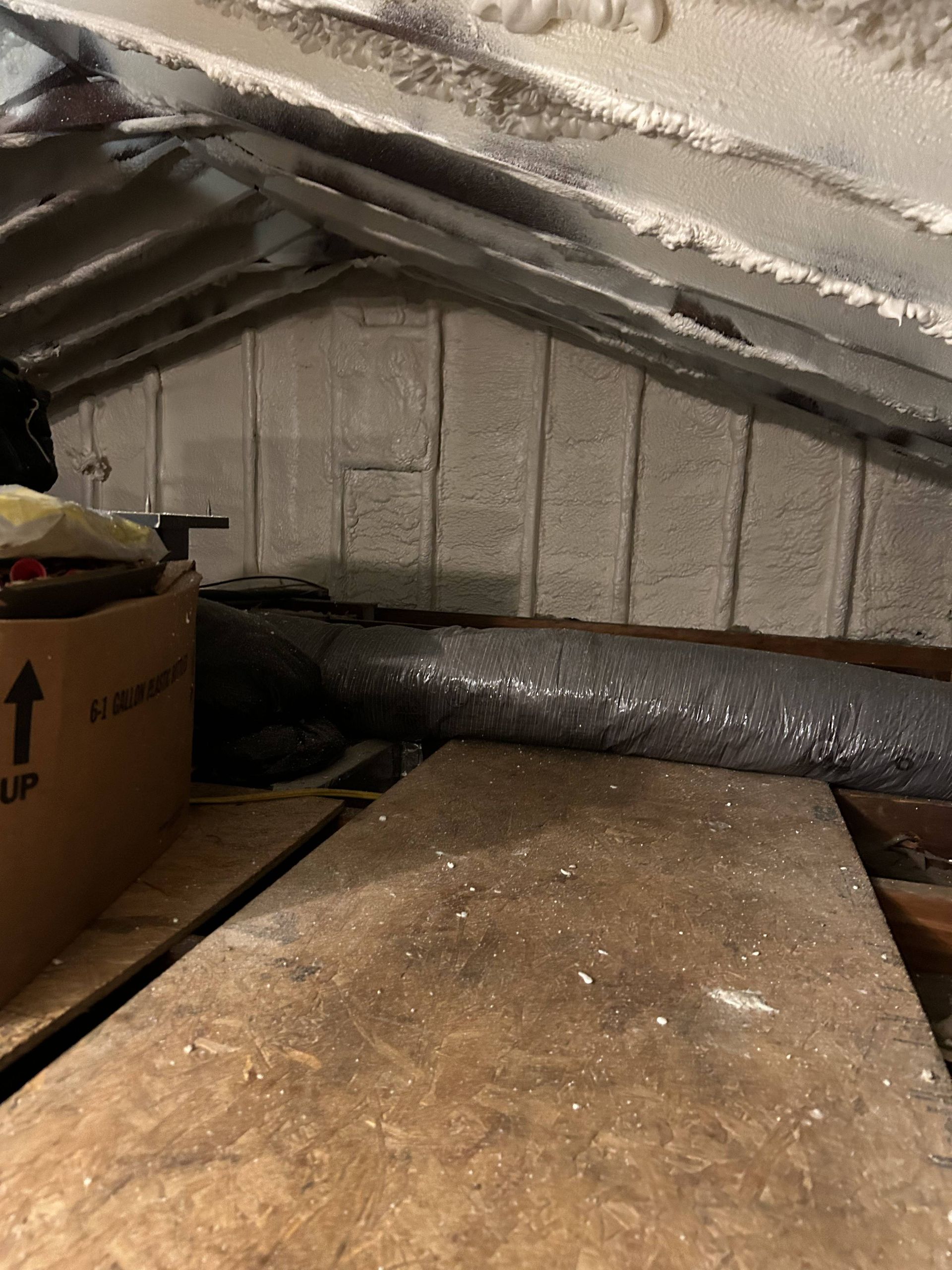 Attic with insulated roof, cardboard box, and wooden boards on the floor