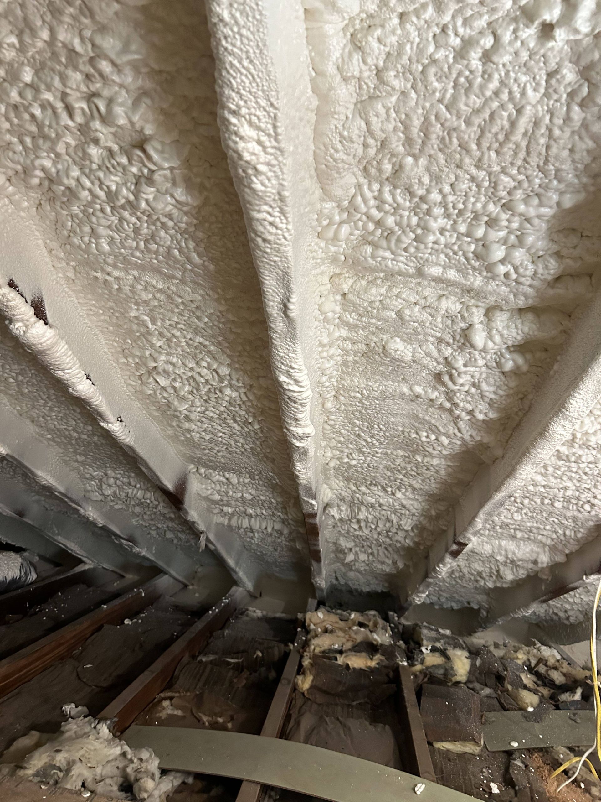 Foam insulation sprayed between attic rafters above exposed wooden framing
