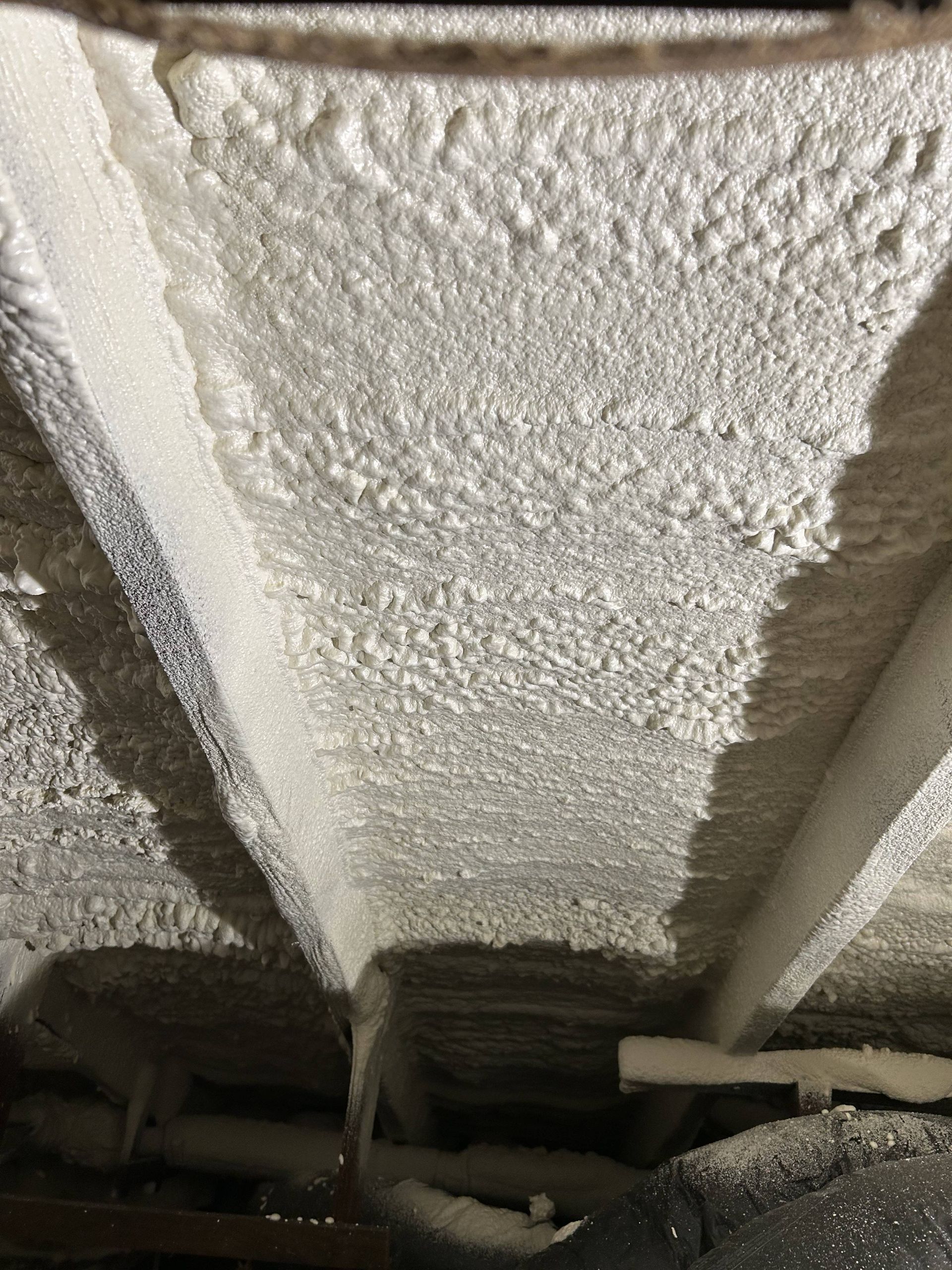 Foam insulation between exposed ceiling joists in an unfinished crawl space