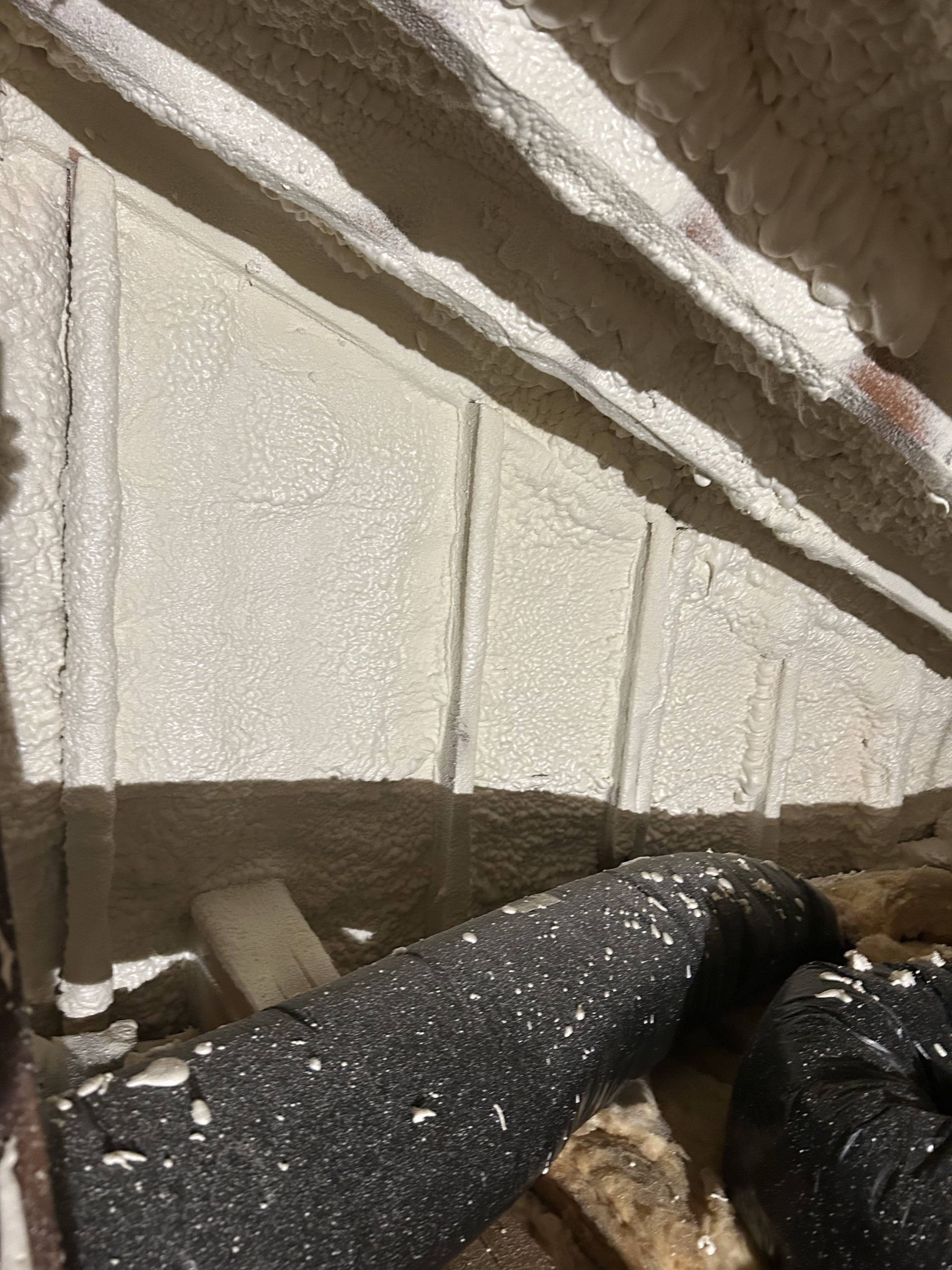 Close-up of a person clearing snow from a white building wall and ledge with a broom.