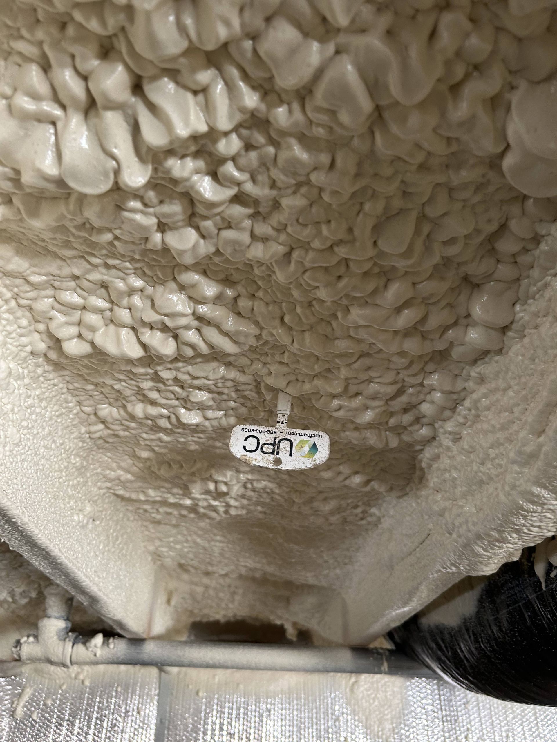 Close-up of a textured white foam ceiling with a small label and a dark object at the lower right