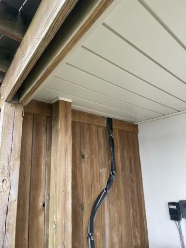 Wood-paneled wall corner with exposed black wiring and white ceiling panels near a sliding door track