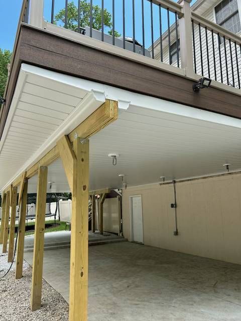 Raised deck with temporary wooden support posts over a concrete driveway or patio area