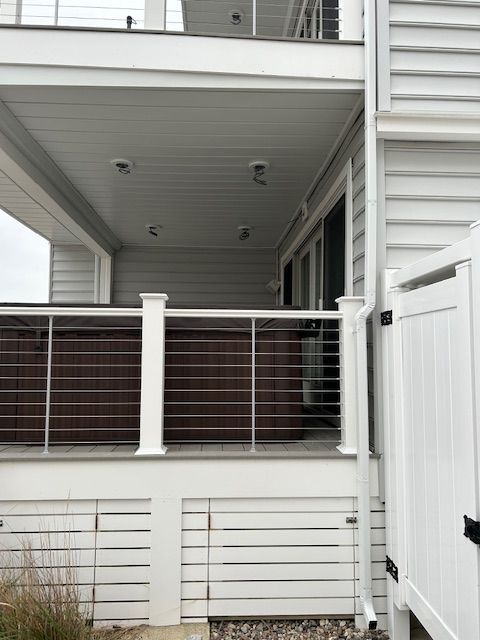 Residential balcony with white siding, dark railing, and fenced patio area