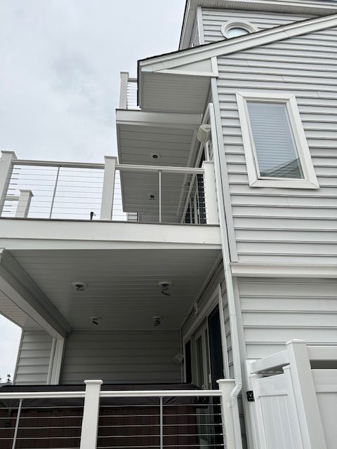 Exterior of a gray multi-level house with balconies and white railings