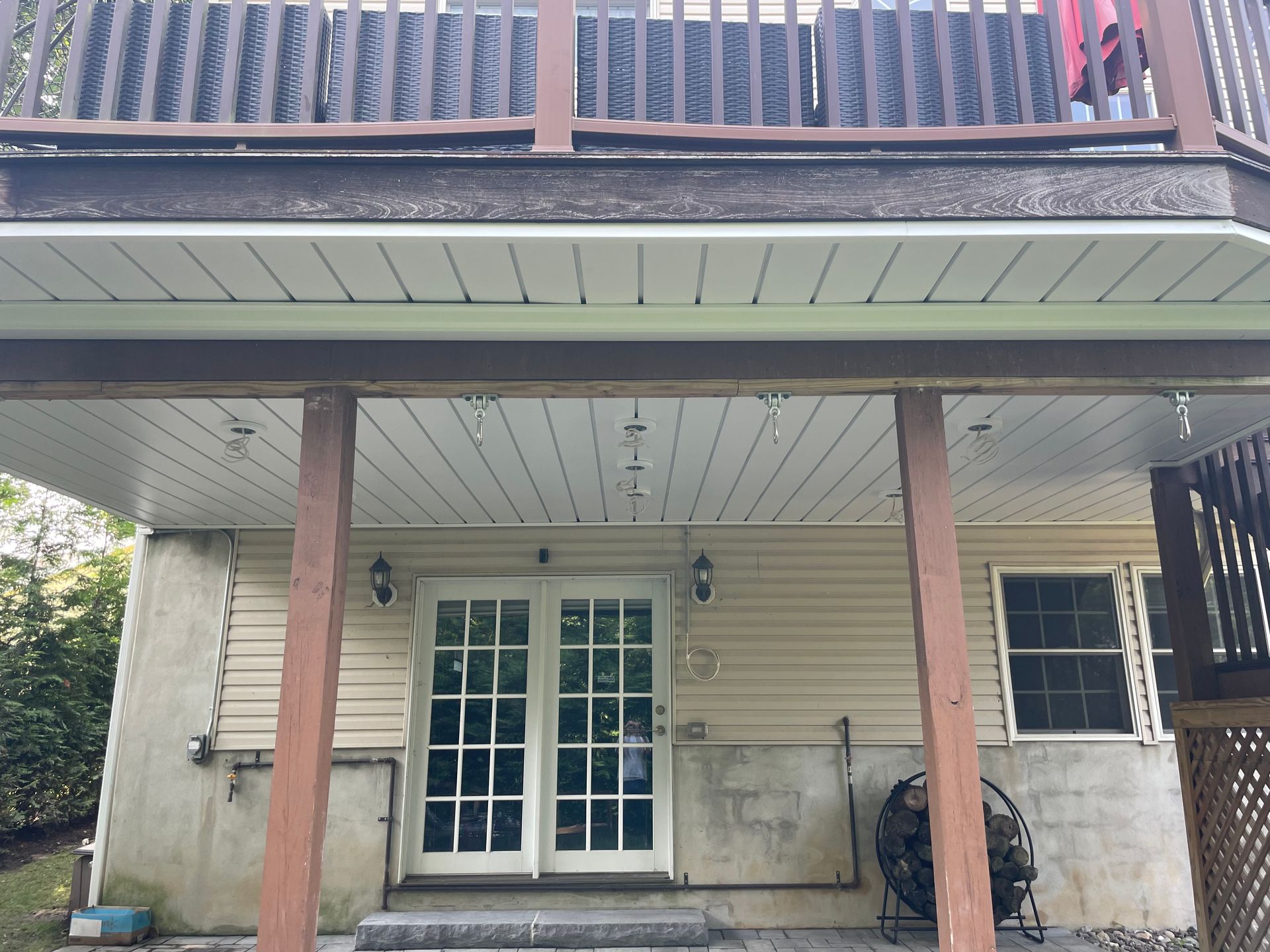 Back porch with French doors, wooden posts, and upper balcony railing