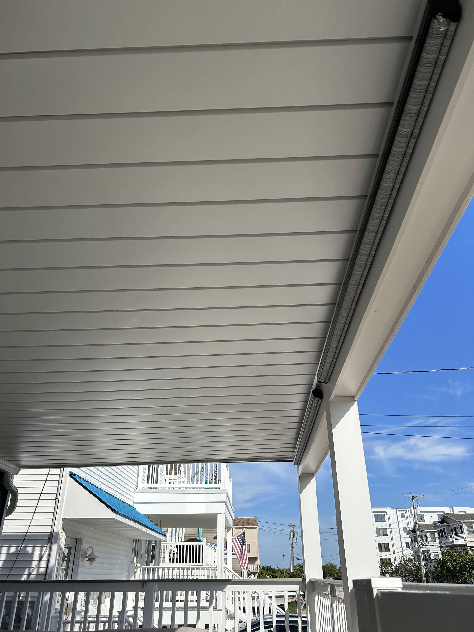 Covered balcony overlooking white buildings and blue sky