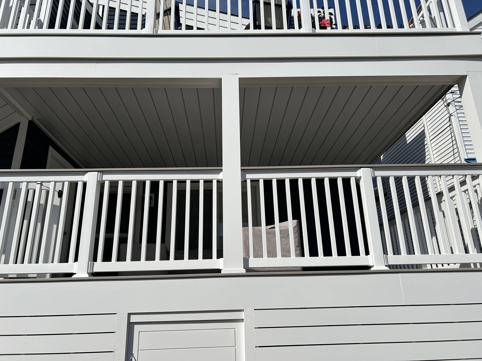 White wooden balconies and railings on a multi-story house exterior.