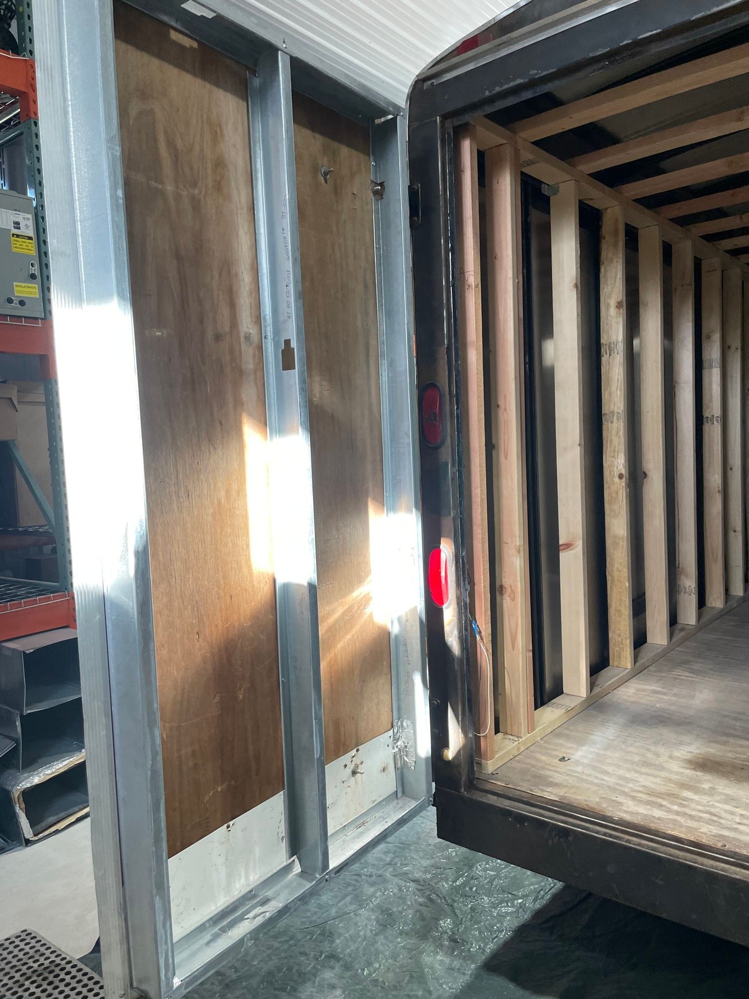 Wooden truck cargo area with open side door and bright sunlight on the metal frame