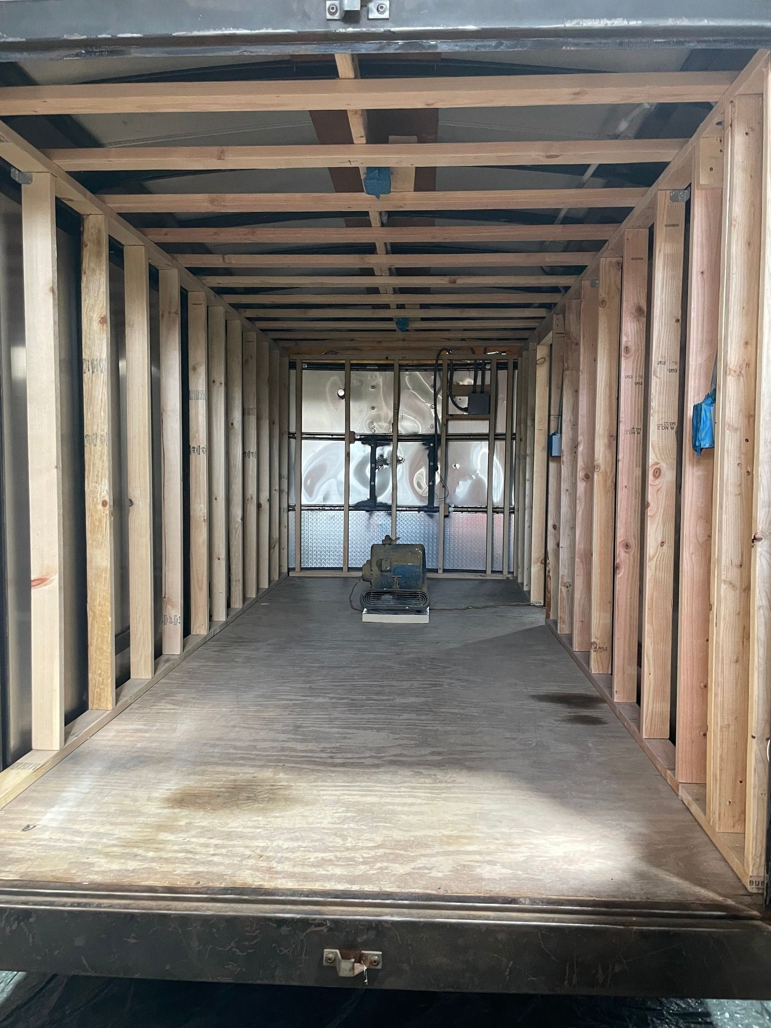 Empty wooden cargo trailer interior with a small tool or machine at the far end