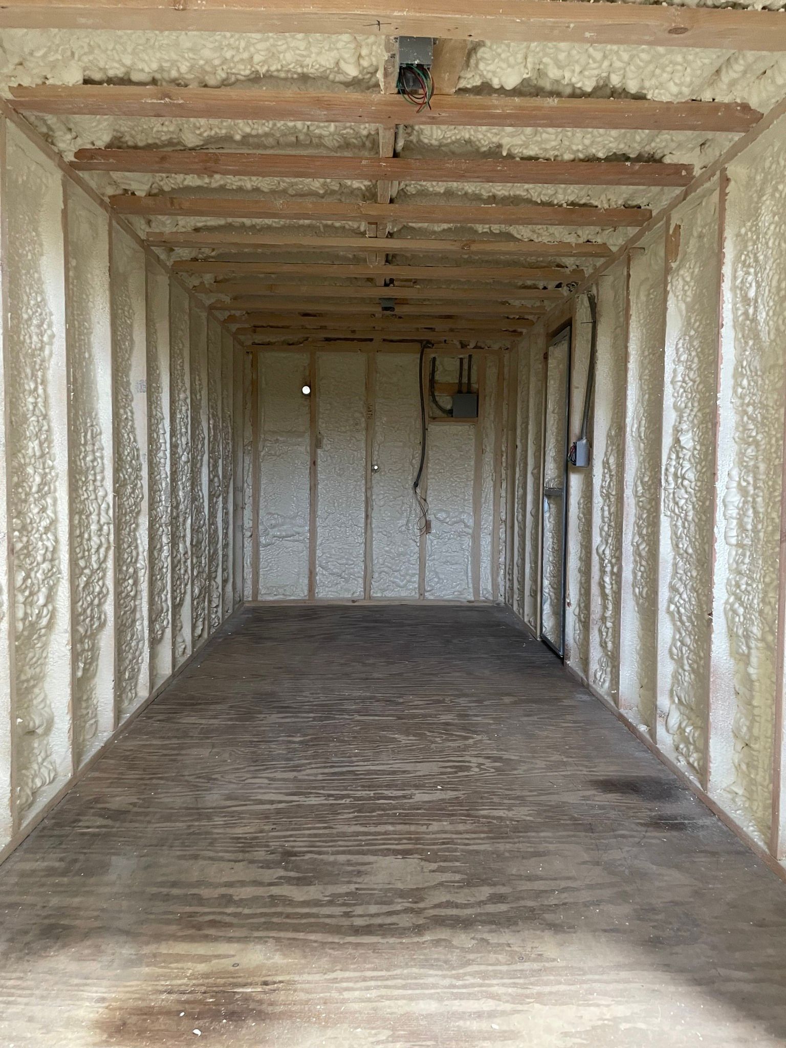 Empty insulated cargo container interior with white walls, exposed beams, and a worn floor