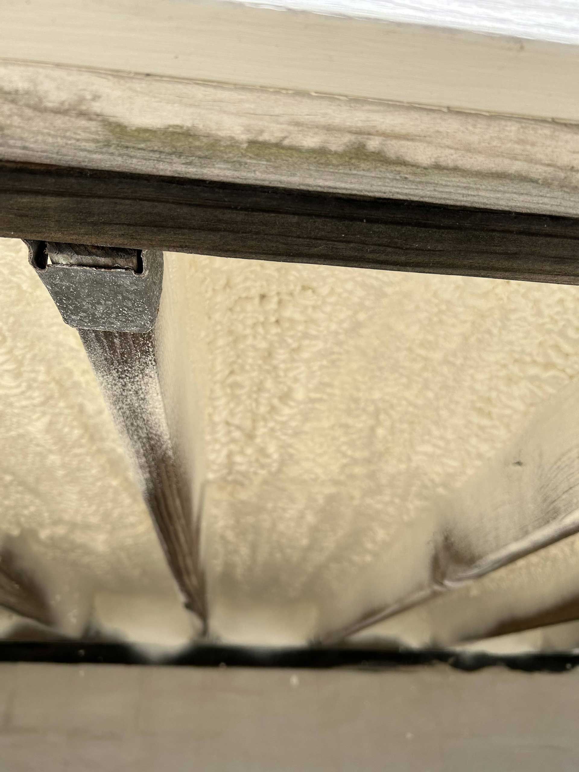 An angled view looking up at the underside of a roof deck, insulated with textured, off-white spray foam insulation.