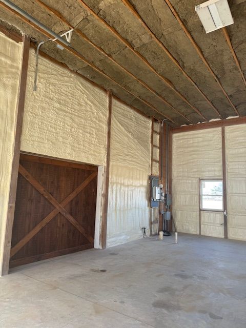 Interior view of a building with spray foam insulation on the walls and ceiling. Wooden door and window.