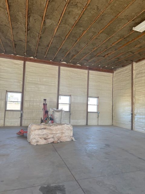 Interior of a building with insulation in walls and ceiling. Windows and large bundle of insulation in the center.