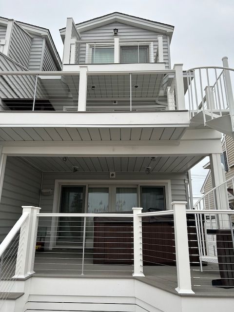 White two-story house with elevated deck, metal railing, and front staircase