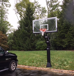 A black truck is parked next to a basketball hoop