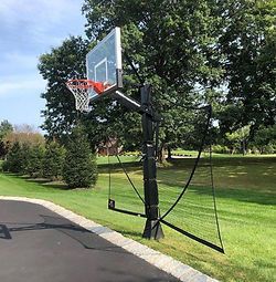 A basketball hoop is attached to the side of a driveway in a park.