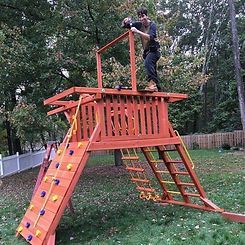 A man is standing on top of a wooden playground.