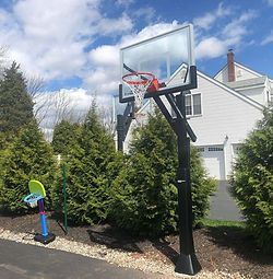 A basketball hoop is sitting in the driveway of a house.